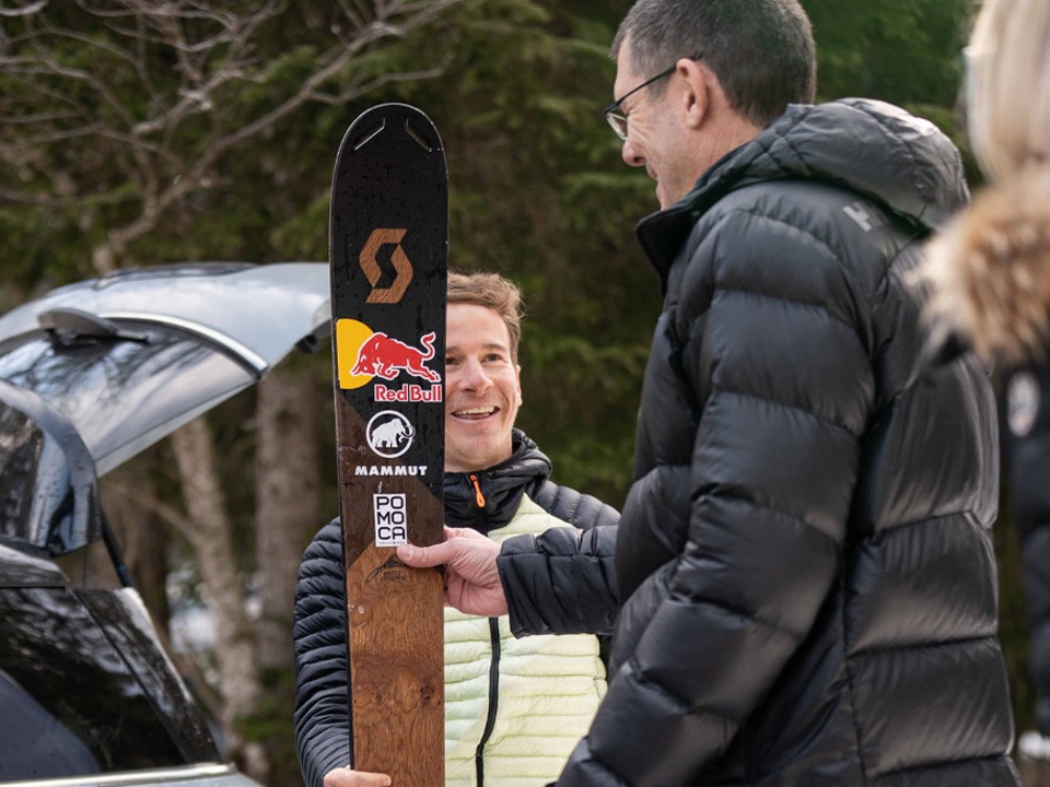 Two men in conversation presenting one set of skis Two men in conversation presenting one set of skis